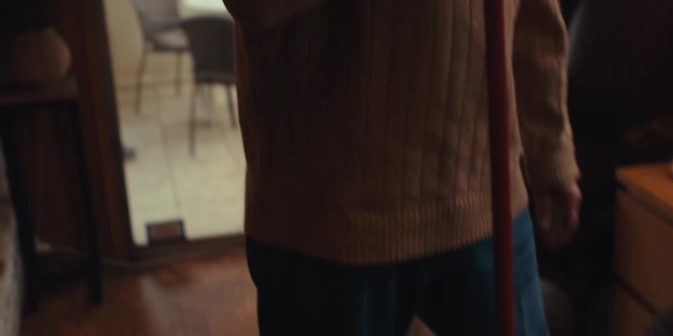 The face of an elderly man who is happy while singing holding a broomstick in a living room
