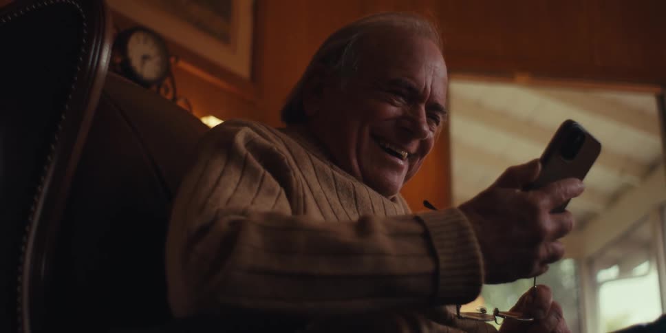 A man laughs while looking at his cell phone