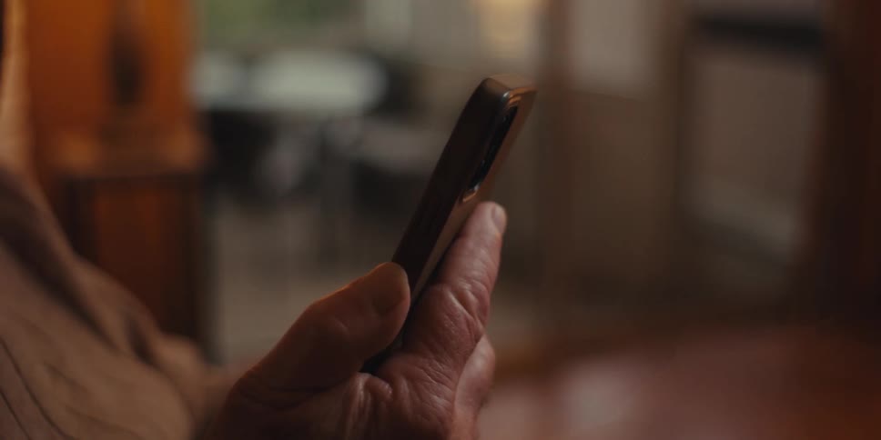 Elderly man sitting focused on using a smartphone