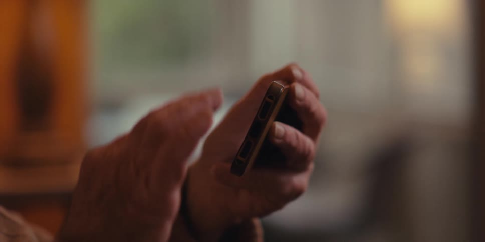 Elderly man sitting in an armchair while interacting with an iphone