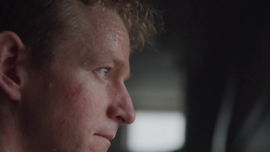 Closeup of a man looking out of a window in a dimly lit room