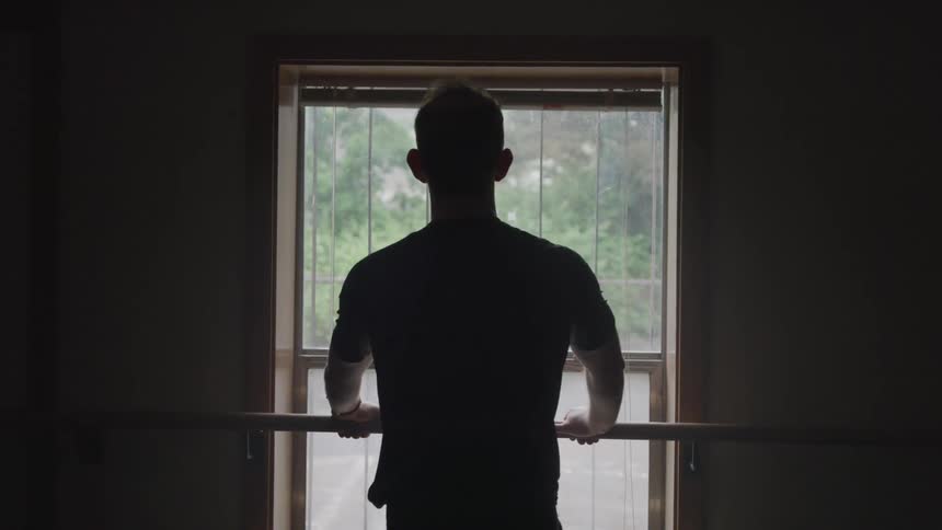 A man is leaning on the window while looking outside