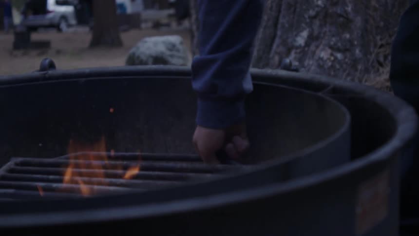 Man places a grill over a fire