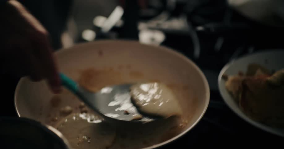 Hand with a spatula turning fried pancakes in a frying pan