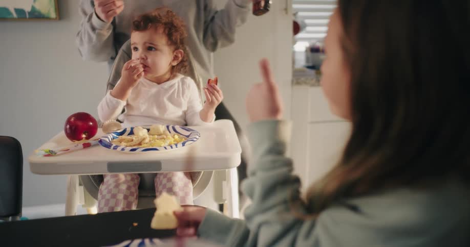 Girl giving thumbs up while eating next to another child