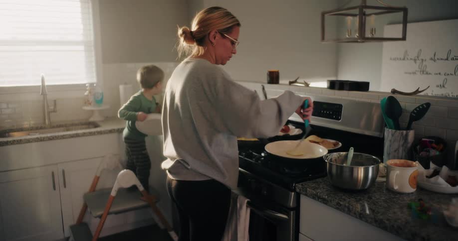 Boy helps his mother in the kitchen while she makes a meal