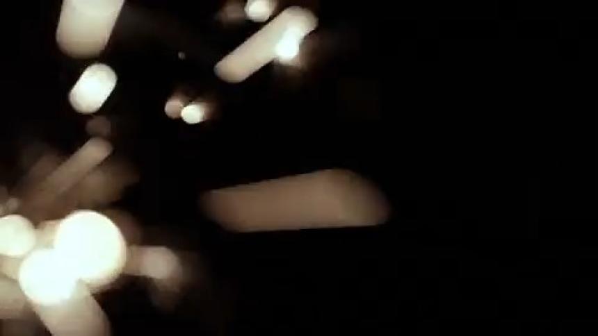 A lit sparkler emitting bright white sparks against a dark background
