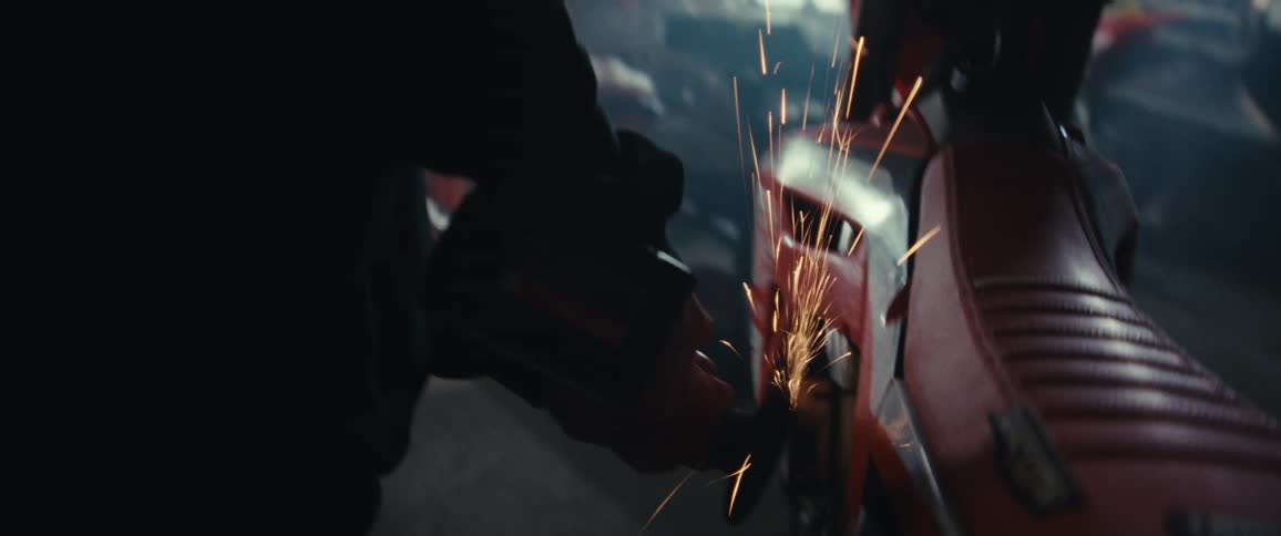 Man applying a tool to the side of a motorcycle and emitting sparks