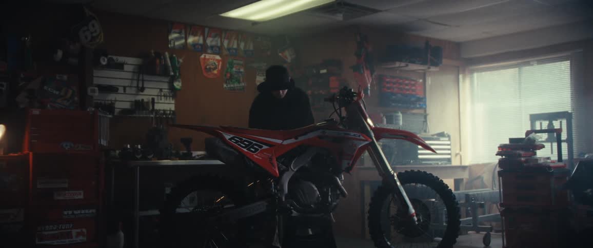 Man working on a motorcycle inside a workshop generating sparks with a tool