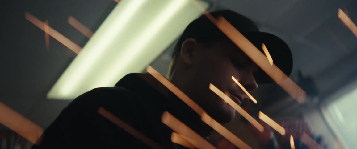 Man in cap working in a workshop with sparks emitting