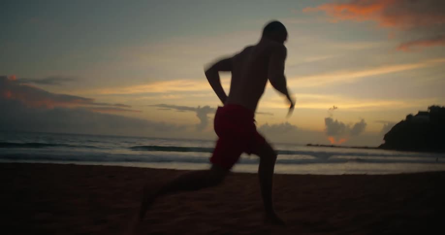 Man running at high heart rate on beach sand in late afternoon