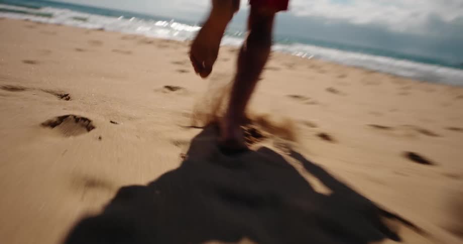 Legs of a person running on the sand towards the sea