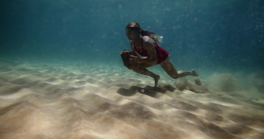 Woman swimming on the ocean floor and carrying an object
