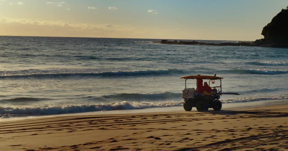 People are riding in a vehicle across the coast of a beach