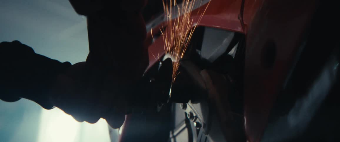 Person using a grinder to adjust a part on a motorcycle