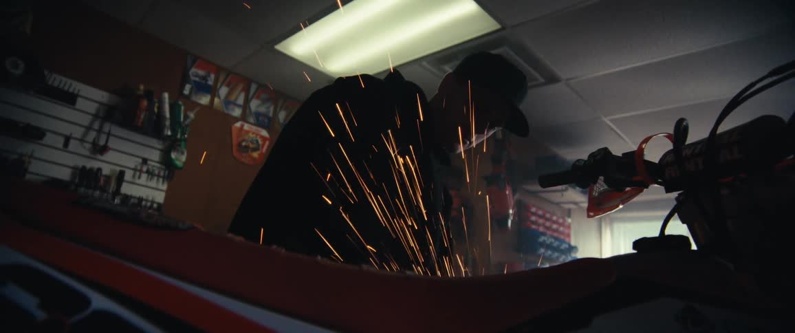 Mechanic using a sparkproducing tool towards a motorcycle in a workshop