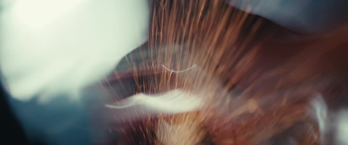 A person wearing a cap is partially visible through streaks of light or sparks