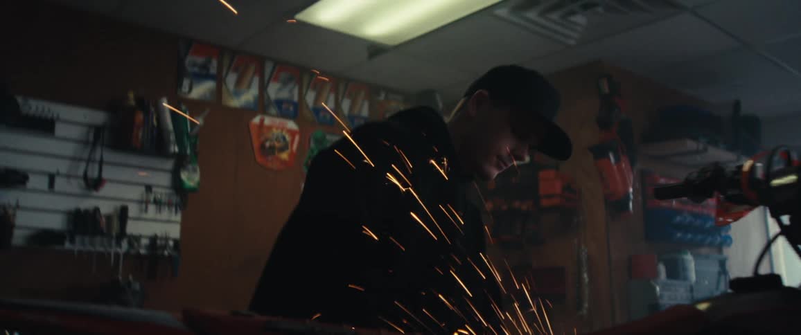 A mechanic is using an angle grinder on a dirt bike