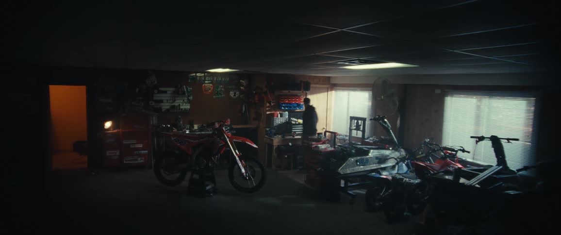 A person prepares a motorcycle for work in a dimly lit workshop