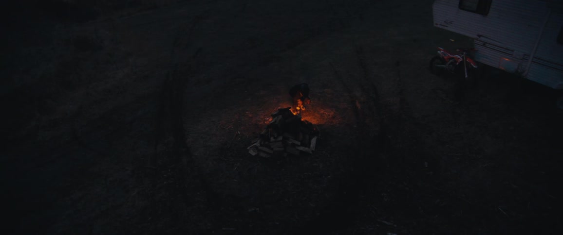 A person uses a torch to light a campfire at night