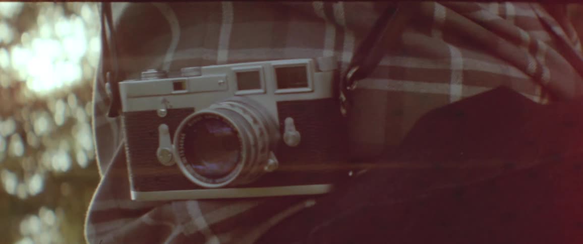 An old camera attached to a persons back by a belt