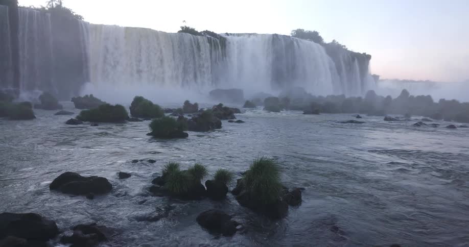 Water plunges powerfully at a large waterfall creating mist and showcasing the force of nature and flowing water