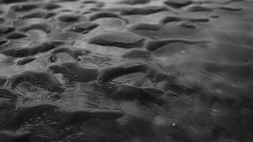Wet sand surface with rain falling