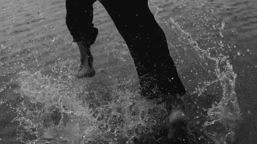 Person splashing as they run through shallow water