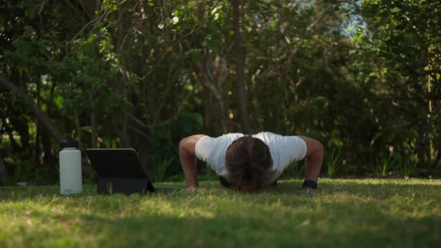 Man in a grassy yard doing pushups