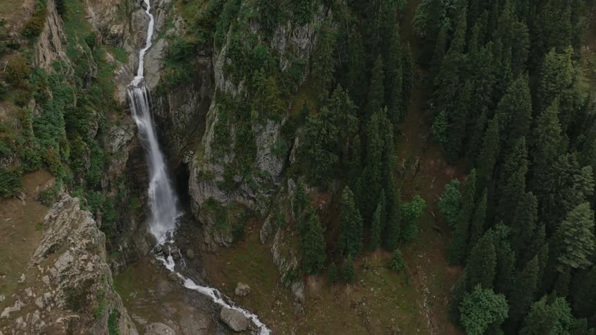 A waterfall pours into a stream on the mountain