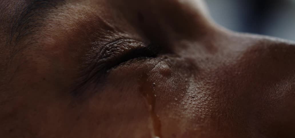 A droplet of water falls near a womans eye and runs down her face