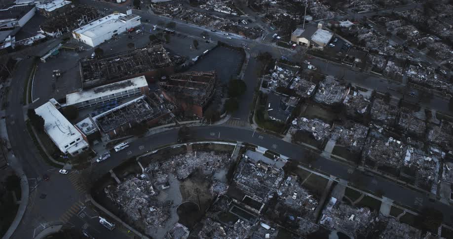 A car drives past the destroyed homes in town