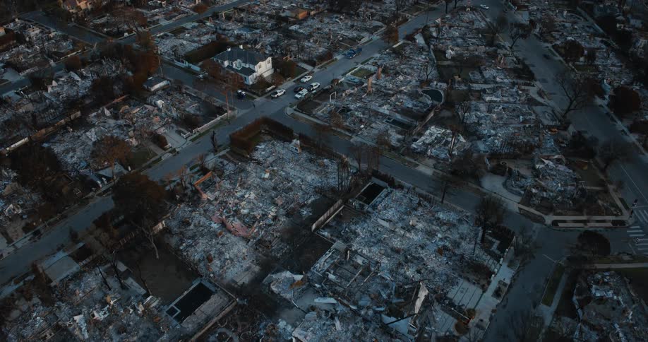 An aerial view of a neighborhood with extensive fire damage where multiple buildings have been reduced to rubble and charred remains