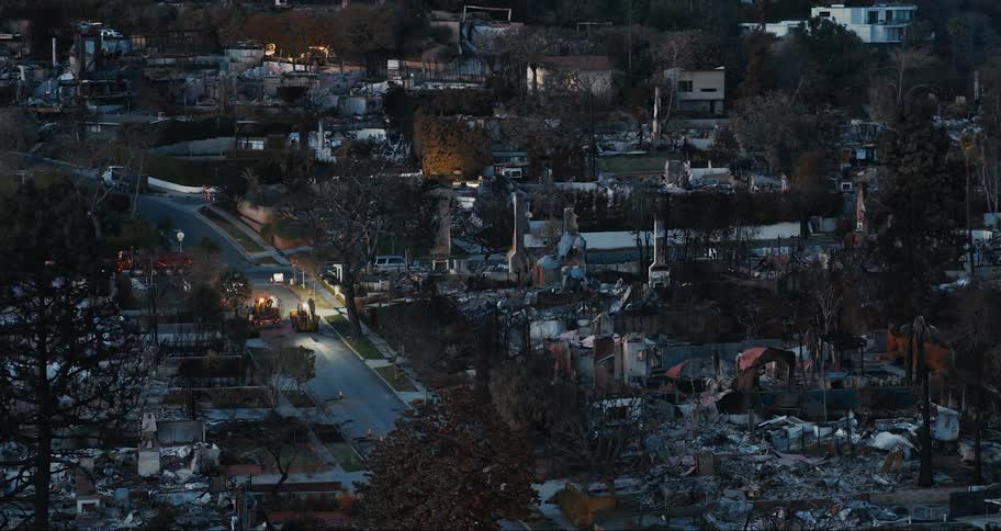 An aerial view of a neighborhood with extensive fire damage where multiple buildings have been reduced to rubble and charred remains