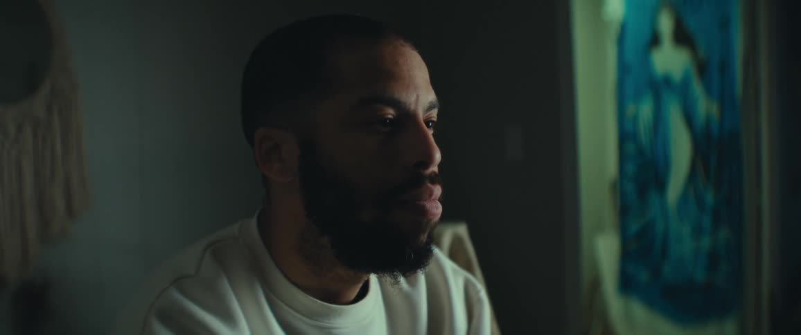 A man is staring forward in a dark room