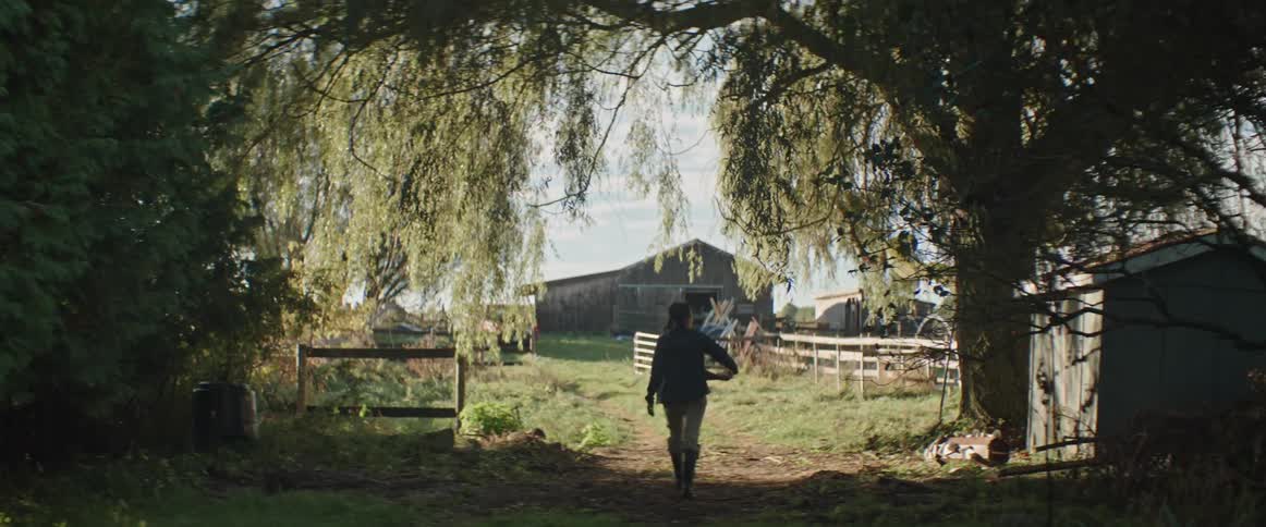 A woman walks towards the barn on the farm carrying a basket