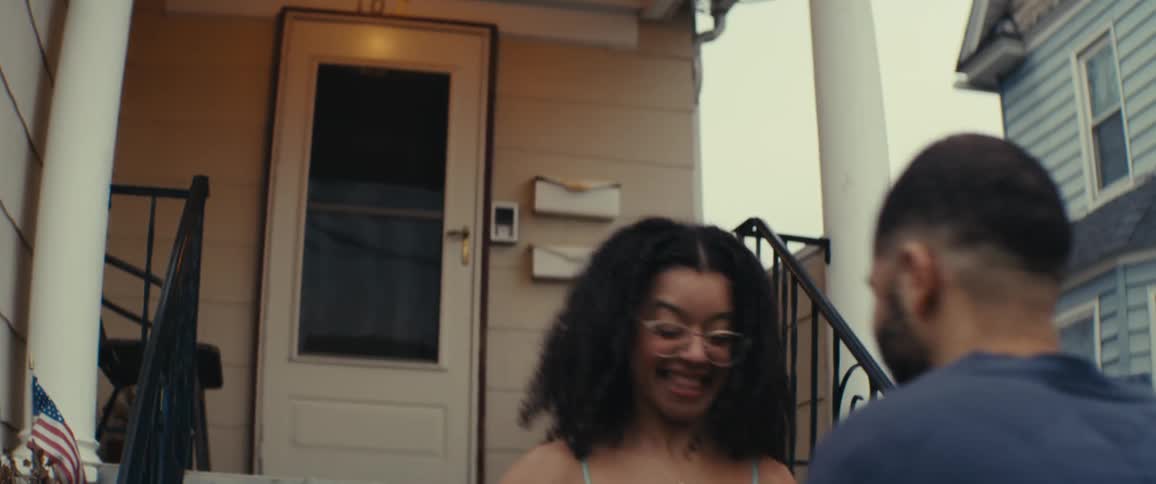 A father looks surprised when he sees his teenage daughter in a shiny blue dress and he hugs her on the front porch
