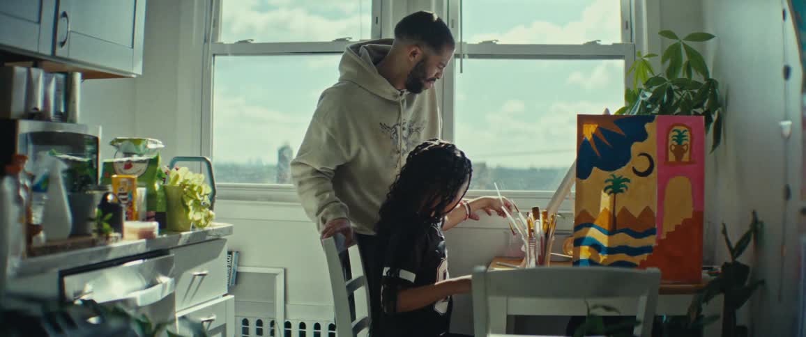 Father watching his little daughter sitting at the table painting