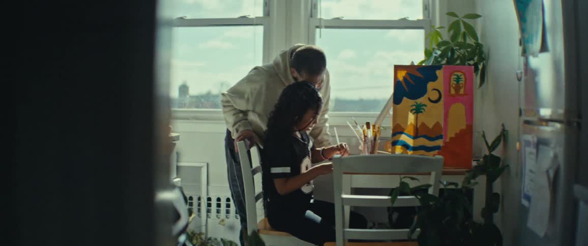 Man accompanying a girl painting a picture
