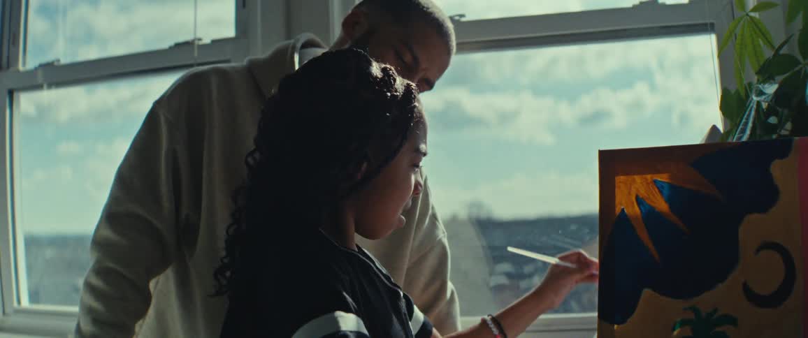 A girl is painting by the window