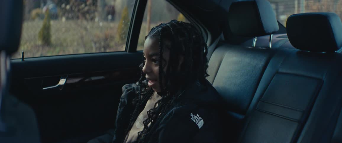 A girl is talking and smiling in the backseat of the car