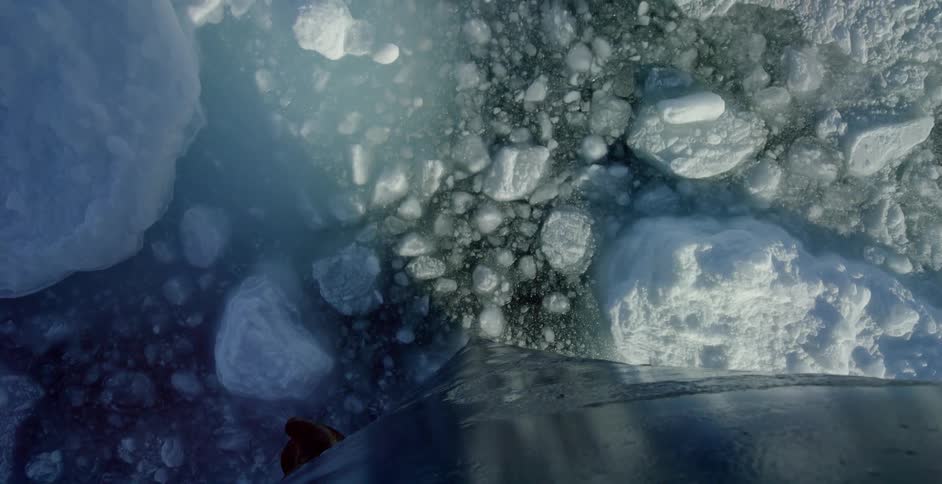 A ship glides through water covered with ice chunks