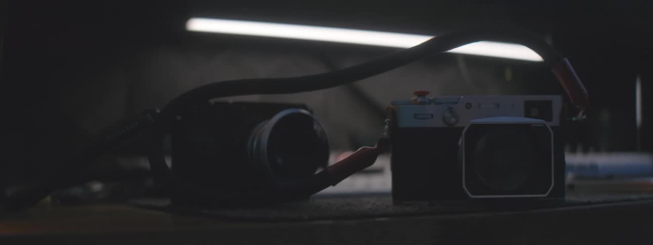 Hand placing one camera next to the other on a wooden surface