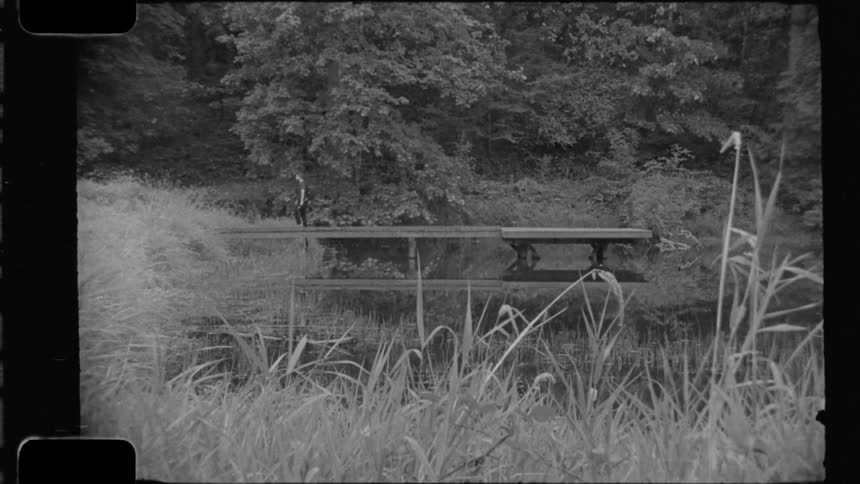 Person putting on backpack and walking off wooden pier into lake
