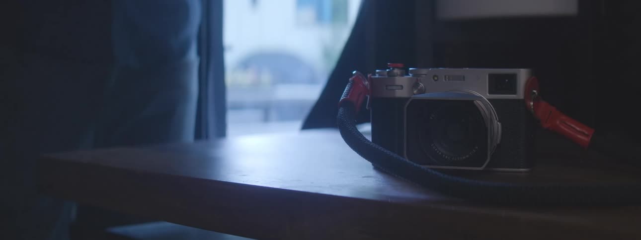 Hand arranging two cameras on top of a wooden table