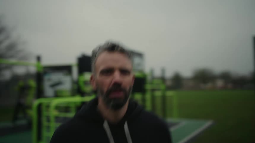 Closeup of a man warming up for jogging in a park on an overcast day