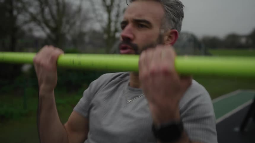 Determined man doing pullups outdoors