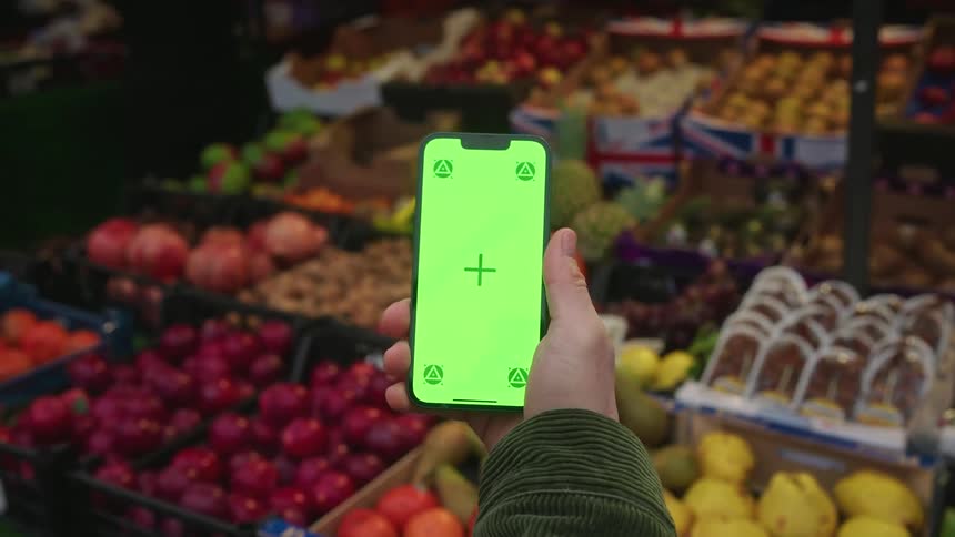 Hand holding a smartphone in a grocery store