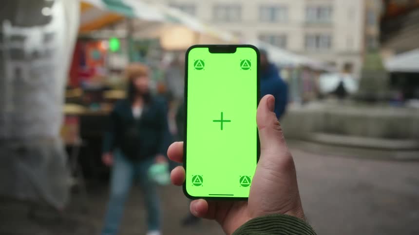 Hand holding a smartphone outdoors in the city