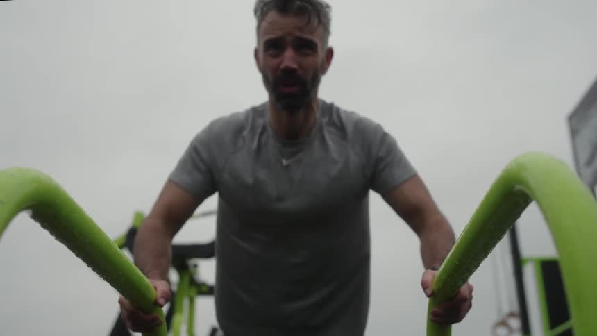 Man exercising on a parallel bar outdoors